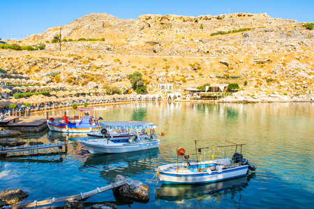 Rhodes, Greece - 14 August 2019: Sunset landscape of beautiful St. Paul's Bay in Rhodes island with mountain, rocky beach and yacht marinaのeditorial素材