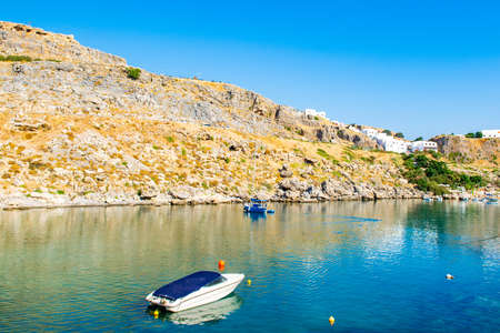 Rhodes, Greece - 14 August 2019: Sunset landscape of beautiful St. Paul's Bay in Rhodes island with mountain, rocky beach and yacht marinaのeditorial素材