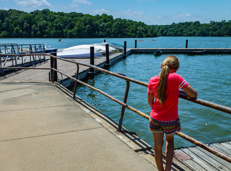 Little girl looking down into the lakeの写真素材