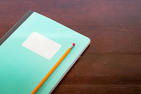Closed notepad with white lable and pencil on a tableの写真素材