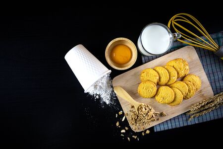 Fresh cookies and ingredients flour, egg, milk and Grains. on black wooden table. Top view.の写真素材