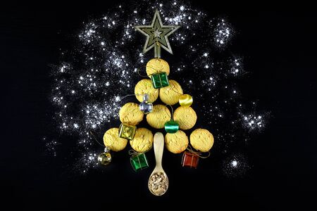 christmas tree made from cookies and wooden spoons with spices on black background. holiday,...