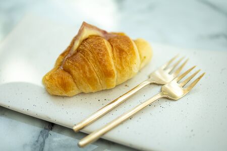 Croissant Bread And two golden forks, Place on a white ceramic plate.の写真素材