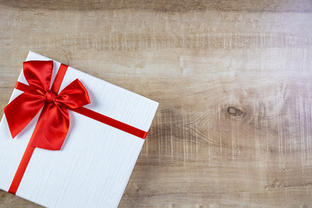 White gift box tied with red ribbon placed on a wooden table. A gift for your special person. Top...