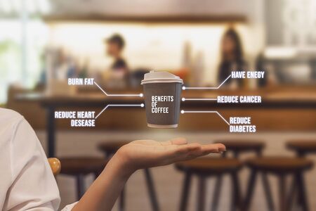 Paper coffee mugs floating on a woman's hand. with benefits of hot coffee in vintage color tone. Blurred coffee shop background.の写真素材