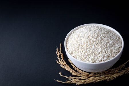 Thai glutinous rice or sticky rice in white ceramic bowl on black background. 45 degree angle. close up shot.の写真素材
