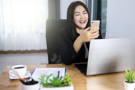 work from home concept. Bussiness woman reading good news on website by smart phone.の写真素材
