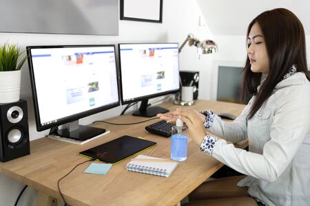 Business woman working from home. Cleaning her hands with sanitizer gel. Business woman in quarantine for coronavirus.の写真素材