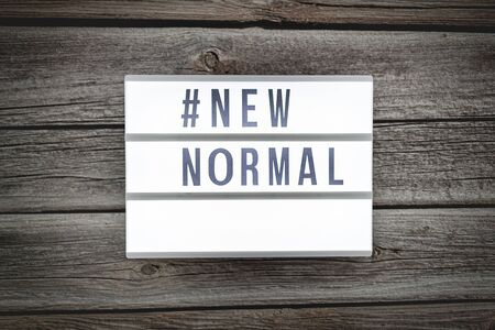 Light box signs with text hashtag #NEW NORMAL on wooden table. New normal concept. Social distancing.の写真素材
