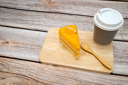 Orange cake with wooden spoon and hot coffee on wooden table. の写真素材