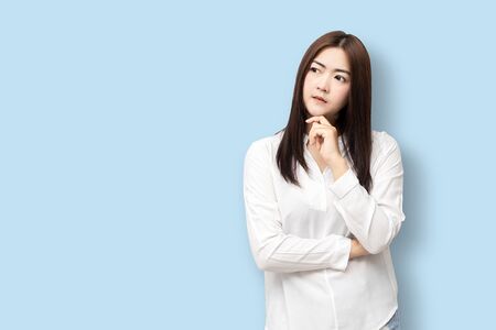 Long-haired Asian women are standing thinking isolated on blue background.の写真素材