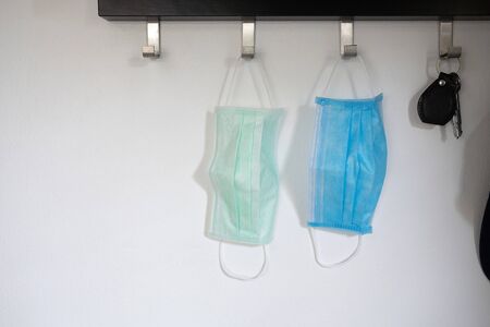 Two sanitary masks hanging on the hook, white and blue color. Corona virus or covid 19 protection.の写真素材