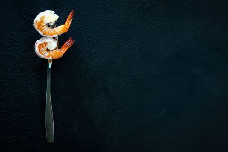shrimps cooked on silver fork on dark texture background.の写真素材