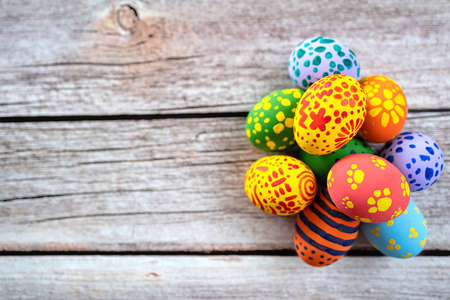 Pile of painted ester eggs in various colors on wooden table. Ester holiday concept.の写真素材