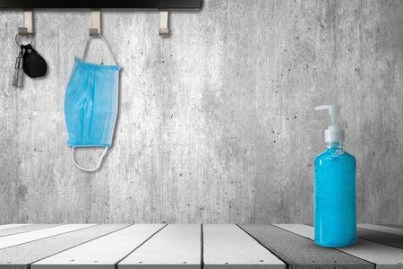 Hand sanitizer bottle and Medical masks on a white wooden table. and Medical masks and key hanging on the hook on cement wall background.の写真素材