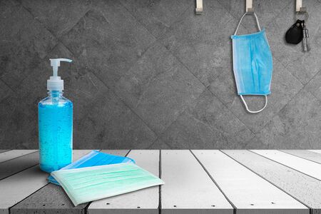 Hand sanitizer bottle and Medical masks on a white wooden table. and Medical masks and key hanging on the hook on Granite tile ceramic background.の写真素材