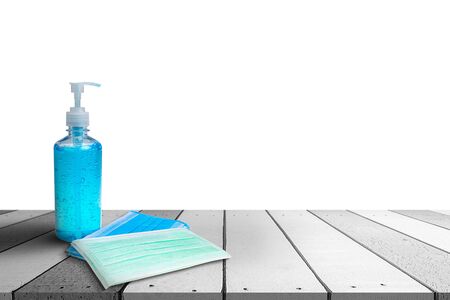Hand sanitizer bottle and Medical masks on a white wooden table isolated on white background.の写真素材