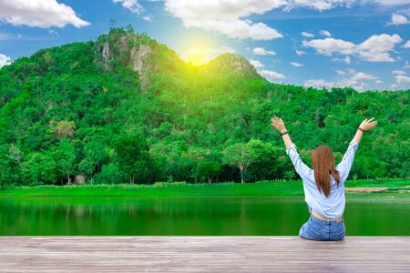 The back of a woman sitting by a large pond. Happy women on vacation.の写真素材