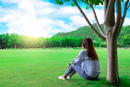 Asian woman sitting under a tree in the park. Sit and rest comfortably on your vacation..の写真素材