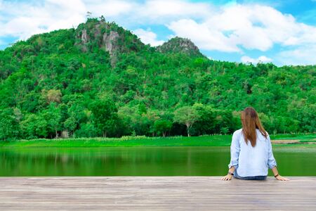 Peaceful lifestyle shot of woman sitting on dock Lake. Sit and rest comfortably on your vacation.の写真素材