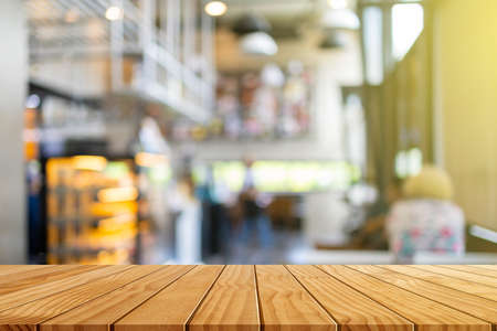 Wooden table in front of blurred coffee shop background with bokeh for background usage.の写真素材