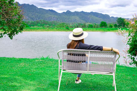 Woman sitting on a bench by the lake with mountain view. Vacation time concept.の写真素材