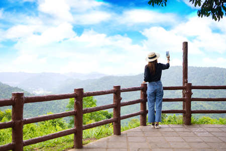 Women wearing a black shirt using their smart phone to record pictures at the mountian.の写真素材