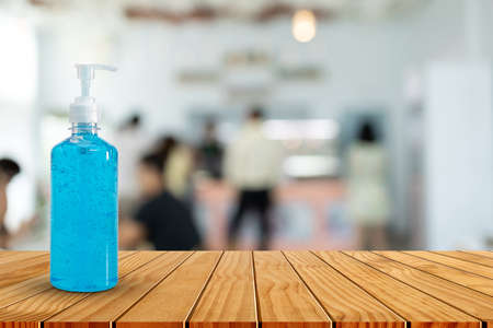 Hand sanitizer bottle on wooden table top in blurred coffee shop. Please wash your hands concept.の写真素材