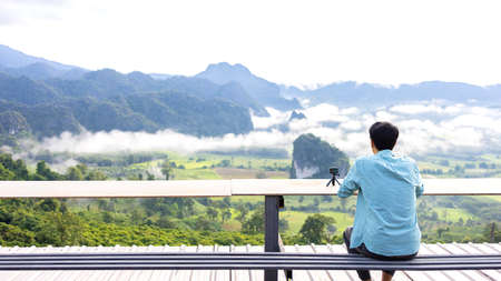 Asian man on the mountain see view panorama the beautiful nature landscape of mountain views and fog on vacation travel.の写真素材