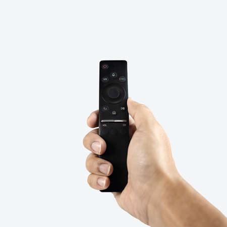 Hand pressing modern remote control isolated on white background.の写真素材