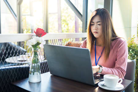 Asian young business women work from coffee shop modern loft,laptop and white coffee cup in cafe.の写真素材