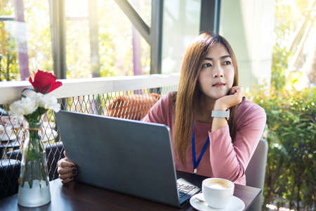 Asian young business women working with laptop and white coffee cup in coffee shop cafe.の写真素材