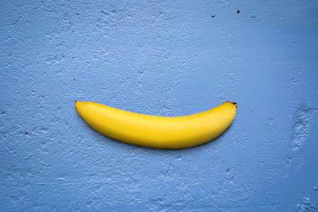 Single banana on blue concrete texture background.