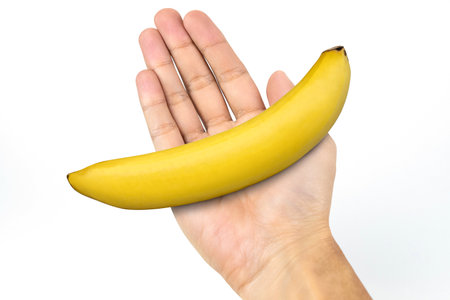 Male hand holding banana isolated on white background.の写真素材
