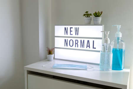 Alcohol hand sanitizer gel in pump bottle and Medical mask with light signs with text hashtag #NEW NORMAL on cabinet, environment and health.の写真素材