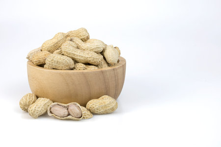 Peanuts in wooden bowl isolated on white background with clipping paths.