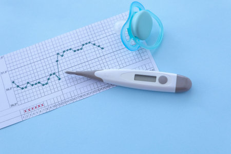 Pregnancy planning. Measurement of basal body temperature. Thermometer, nipple, temperature graph on...