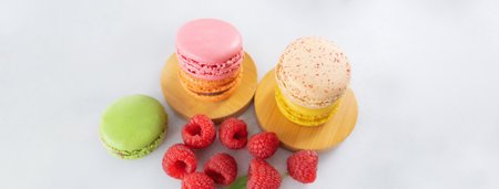 Colored macaron, French macaroon, French traditional cookies and raspberries on a light background. Dessert for tea, sweet breakfastの写真素材