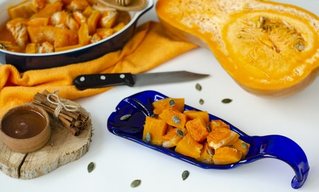 Baked pumpkin on a hand crafted blue serving plate on white background. Copy space. Healthy eating and diet concept.の写真素材