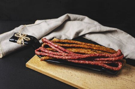 Polish traditional thin sausages kabanos on black background on a plate made from bottle. Copy space. Fat food concept.の写真素材
