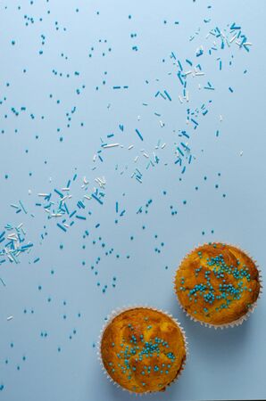 Muffins decorated on pastel blue background. Top view.Copy space. Holidays and greeting card concept. Vertical.の写真素材