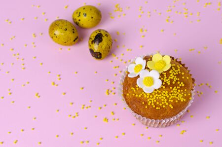 Muffins decorated with flowers of mastic and yellow quail eggs on pastel pink background. Top view. Copy space. Holidays and greeting card concept.の写真素材