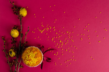 Easter muffin decorated with ribbon and sprinkles, yellow quail eggs and a branch of apricot tree on...