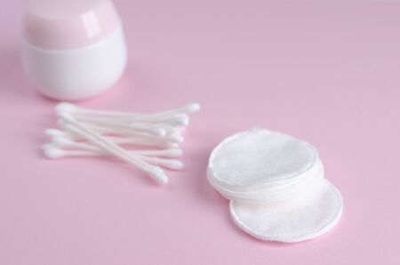 Ear sticks and cotton pads on pastel pink background. Makeup removal and skin care concept. Space for textの写真素材
