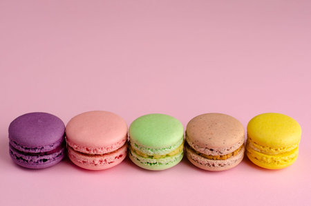Colorful sweet french dessert macaroon or macaron on pastel pink background. Space for text....