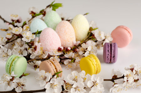 Decorative Easter eggs and sweet macarons or macaroons decorated with blooming apricot flowers on...