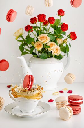 Fresh bouquet of roses, flying macarons and splashing tea on white background. Food levitation concept. Valentines Dayの写真素材