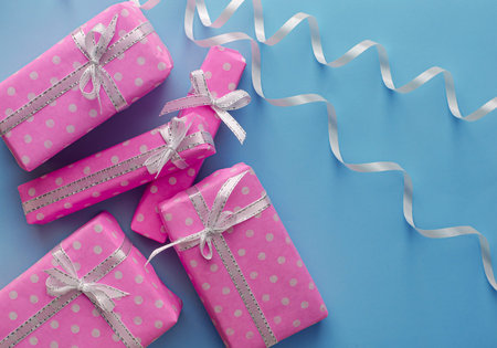 Gift or present pink boxes with ribbon on pastel blue background. Flat lay composition for holidays...