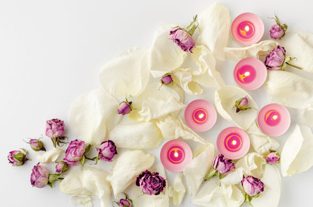 Harmony concept. Burning aroma candles, dried roses and petals on white background. Flat lay, copy spaceの写真素材