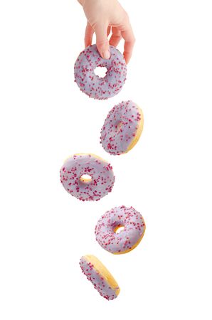 Flying purple donut with female hand isolated on white. Food levitation concept.の写真素材